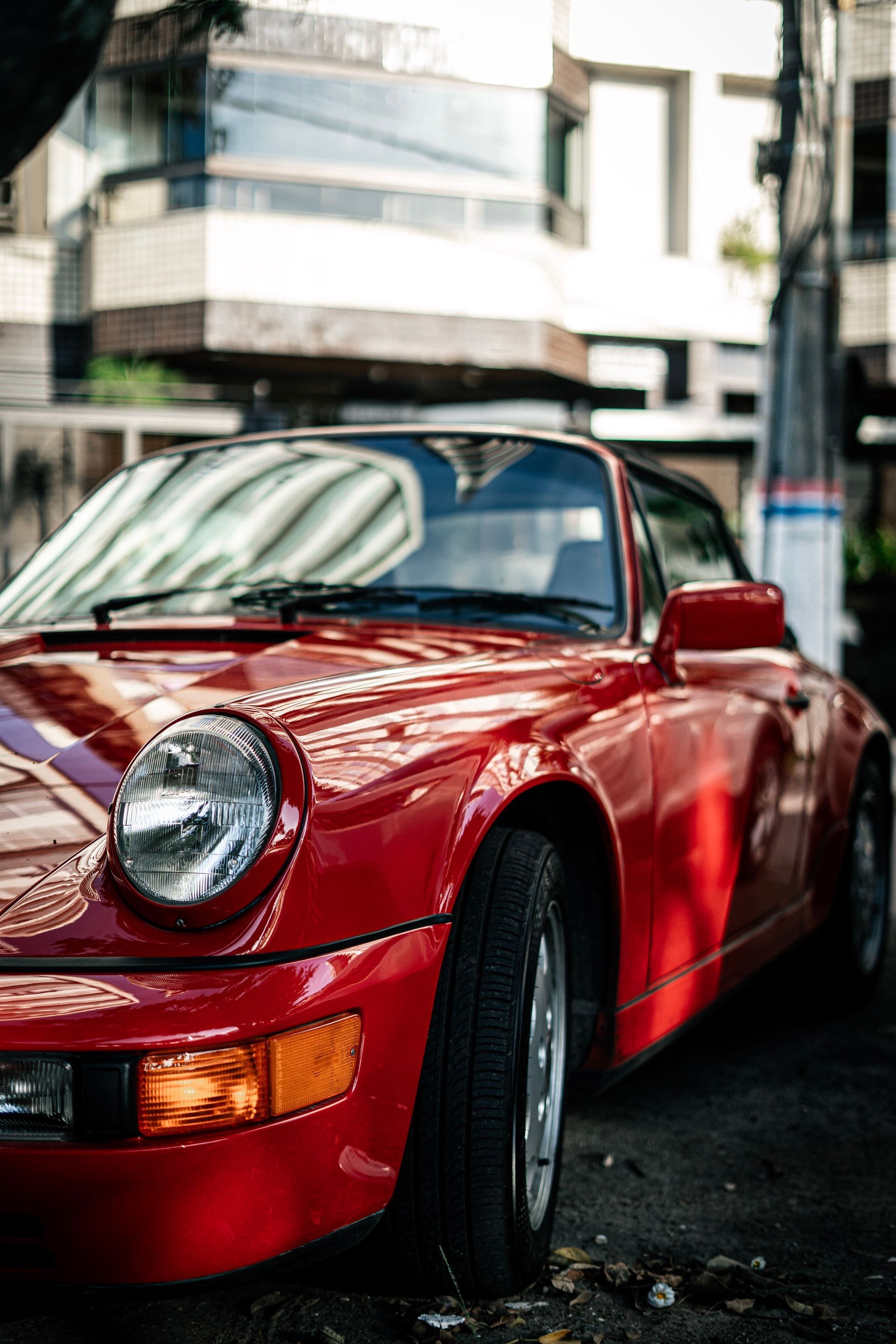 Cabriolet rouge, aile avant et phare ronds, garé en ville